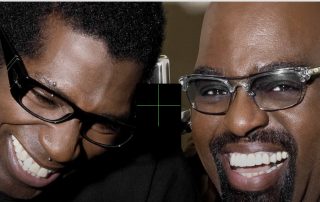 Two men smiling for a close-up selfie, wearing glasses and leaning in together.