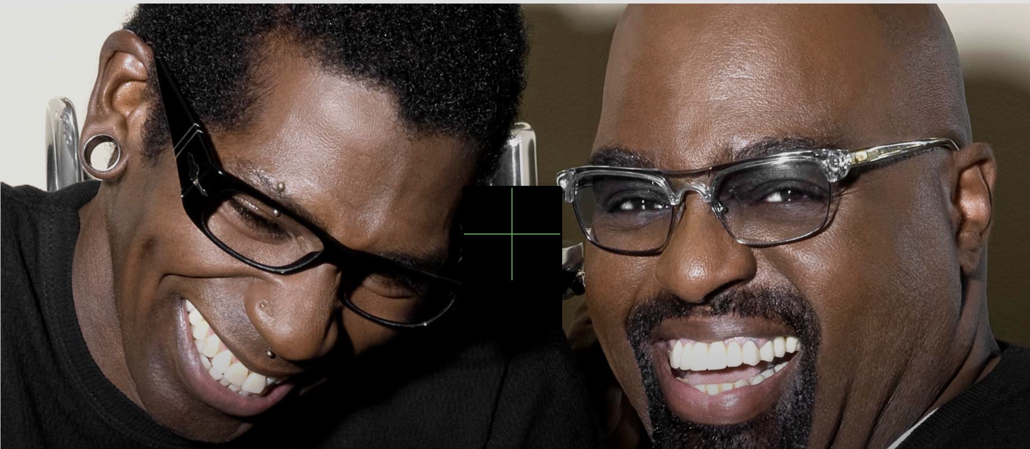 Two men smiling for a close-up selfie, wearing glasses and leaning in together.