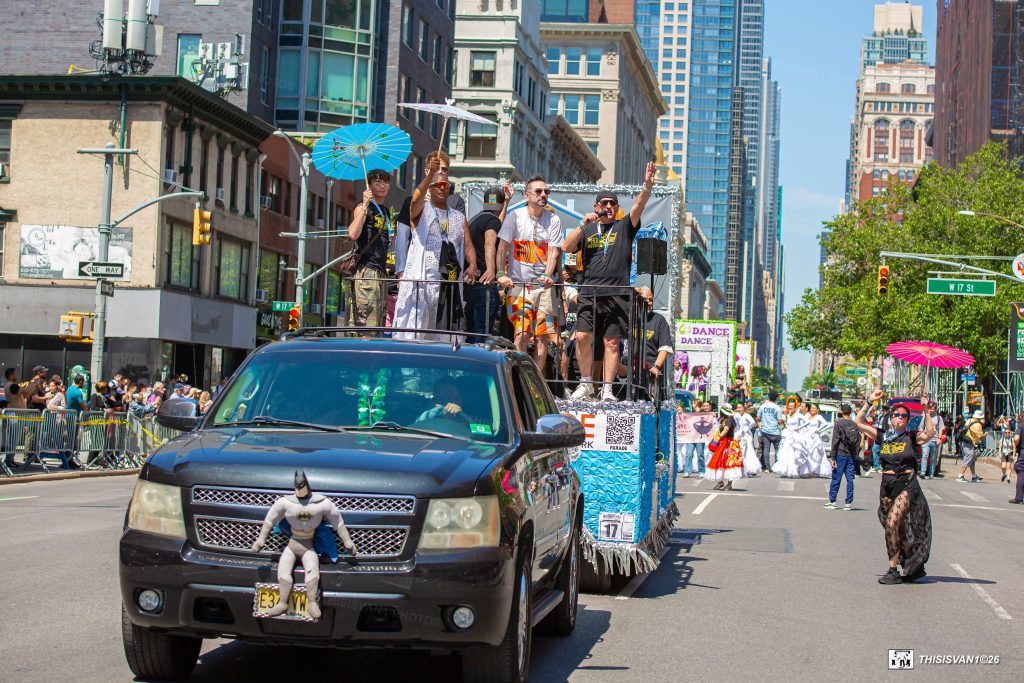 My House Radio 2026 Dance Parade float atop a black SUV with performers waving from a decorated platform on a city street with spectators along the curb
